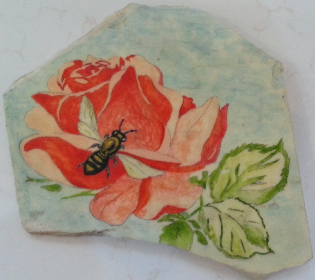 A red rose with a bee, painted on an irregular hand-cut stone